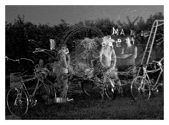 A time-lapse photo of kids playing with sparklers and bicycles